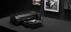 Canon PRO-300 printer on a black table with prints on the wall