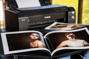 An open photo album in front of a Canon printer