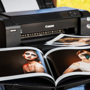 An open photo album in front of a Canon printer