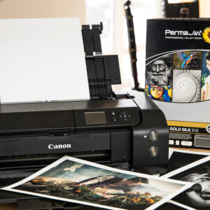 Canon printer with a box of PermaJet FB Gold Silk paper and two prints