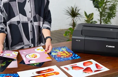 Woman holding prints next to a Canon printer